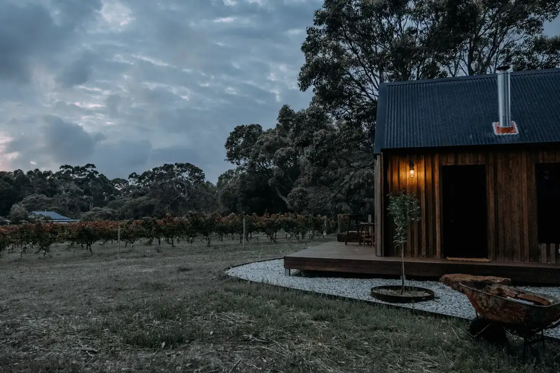 Small timber cottage at dusk with warm light in the windows