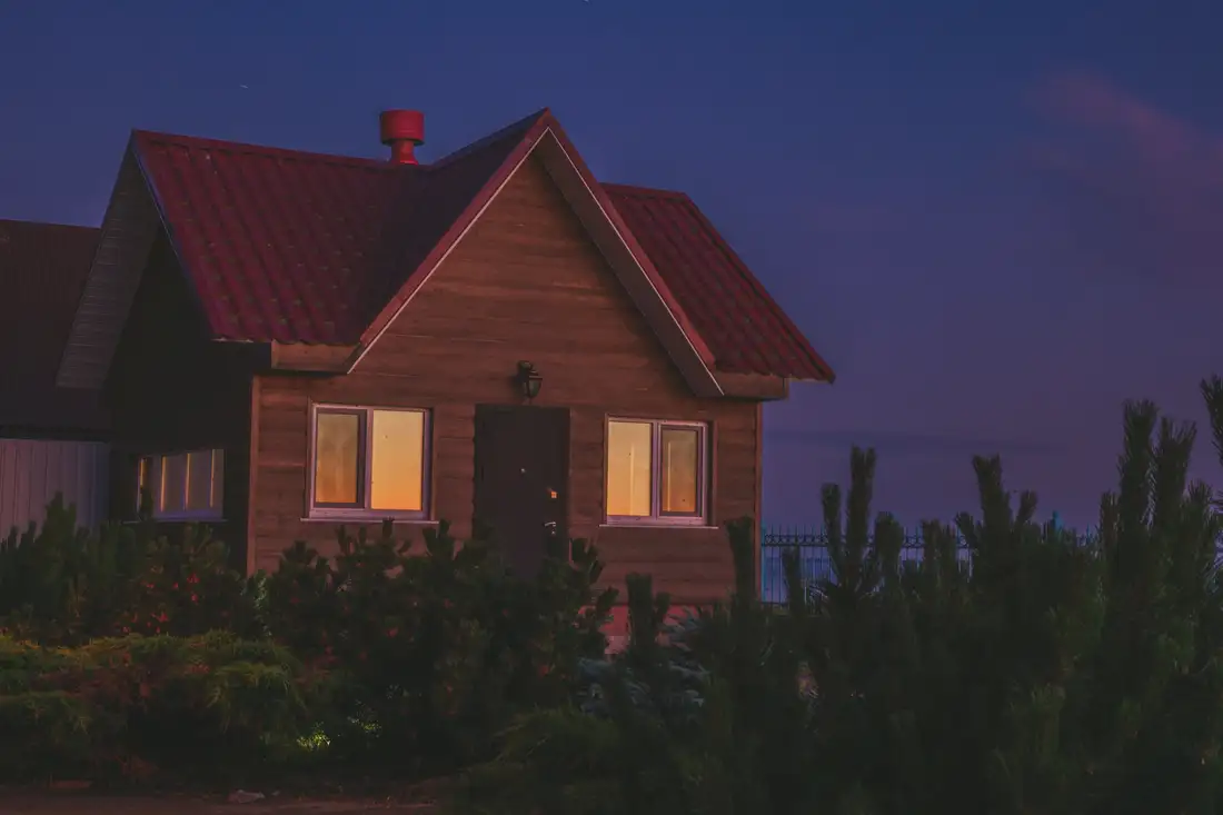 Gabled timber house at dusk with lights in the windows