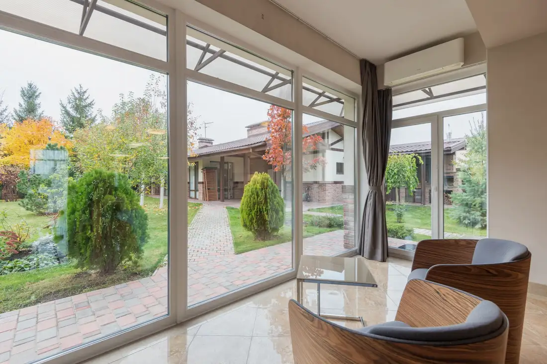 Backyard seen through a large window, with a path and shrubs