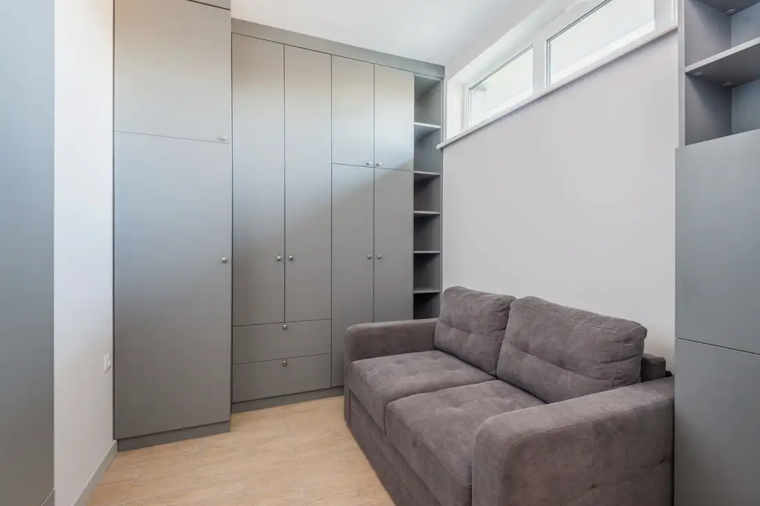 Compact finished room with built-in wardrobes and a grey sofa
