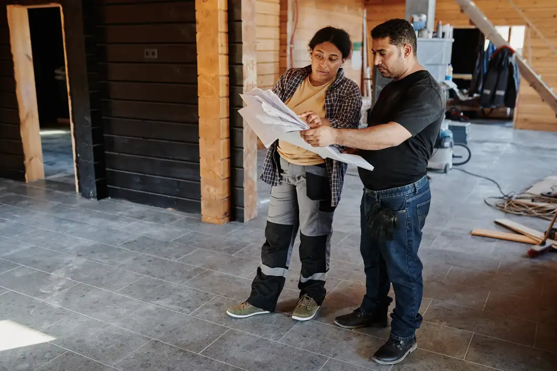 Two builders reviewing drawings in a house under construction