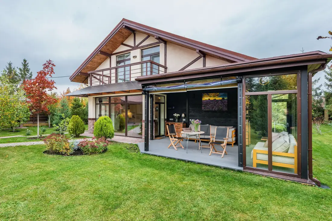 House with an attached glass-walled wing opening onto a lawn